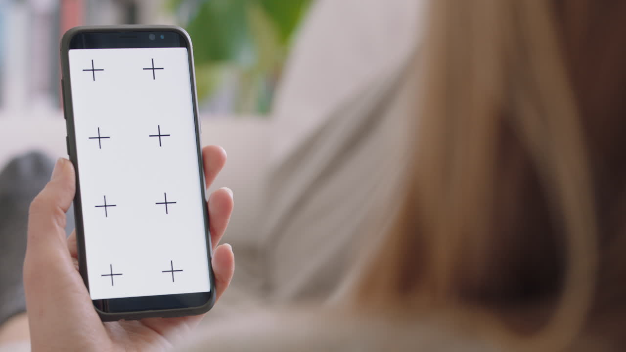 giovane donna che usa lo smartphone guardando lo schermo verde godendosi l'intrattenimento sul telefono cellulare display chiave croma orientamento verticale filmato 4k