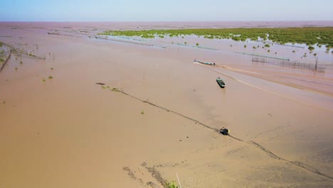 Aerial-drone-view-fly-over-fisherman-mending-nets,-fish-traps-and-boat-heading-out-to-the-horizon-of-this-immense-and-largest-fresh-water-lake-in-South-East-Asia,-Tonle-Sap