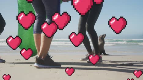 animación de corazones de píxeles rojos flotantes, sobre mujeres recogiendo basura en la playa con foca