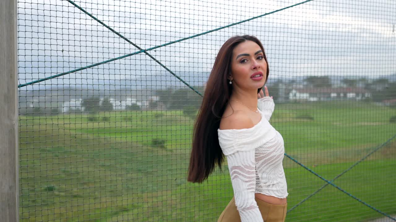 Woman posing outdoors near a fence