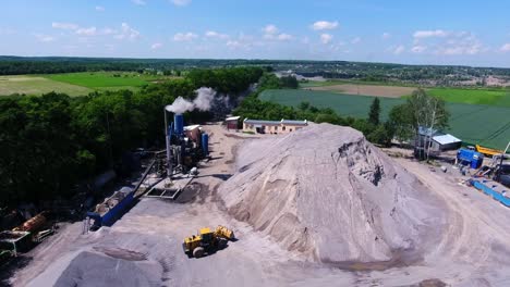 top view of a working asphalt plant with a bulldozer. a large mound of gravel