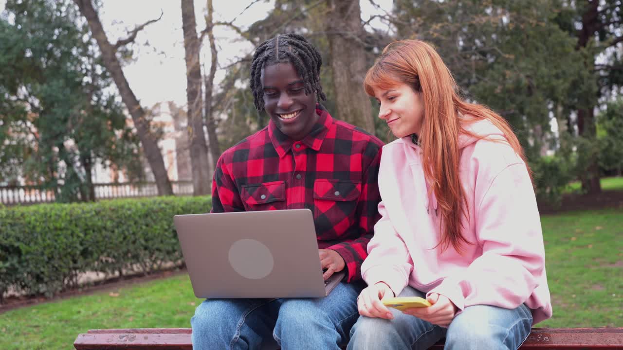 Due giovani studenti che lavorano su un laptop nel parco