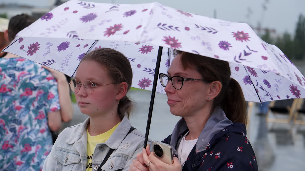 어머니와 딸은 비가 오는 동안 우산 에 있습니다.