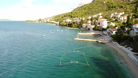 aerial towards pier at beach miosici in the village of brist, dalmatia, croatia