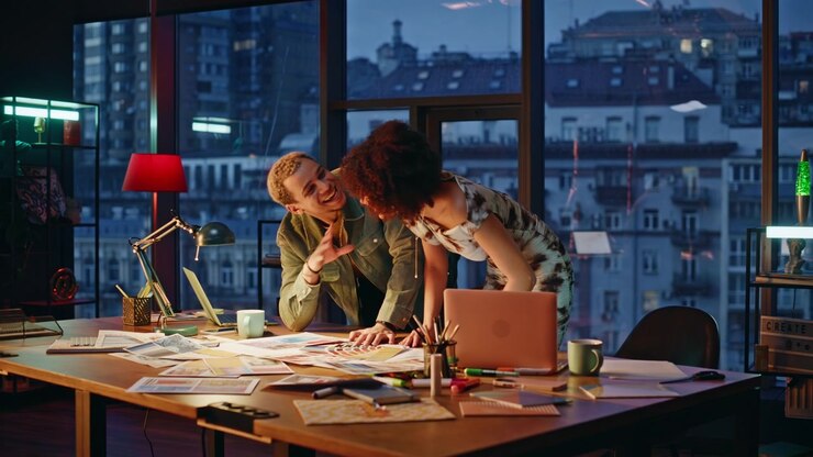 To designere diskuterer fargepalettprøver i kveldsåpent kontorstudio