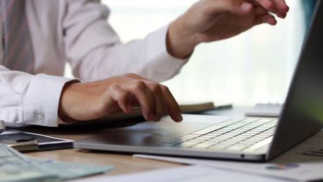 un hombre escribiendo en un teclado de portátil, está usando un portátil para escribir un mensaje y enviarlo a un colega, presiona el teclado del portátil. metraje 4k.