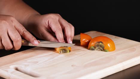 hands carefully slicing a ripe persimmon