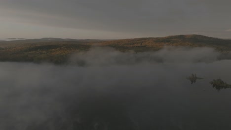 la antena en órbita del lago onawa revela la montaña de roca perforada a través de la niebla que se levanta