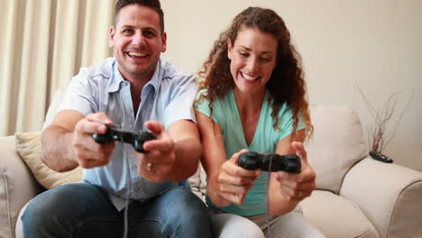 una pareja feliz sentada en el sofá jugando videojuegos.