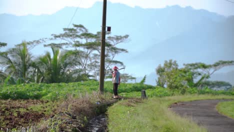 slow motion - a farmer bring hoe is walking to plantation with beautiful view of hill