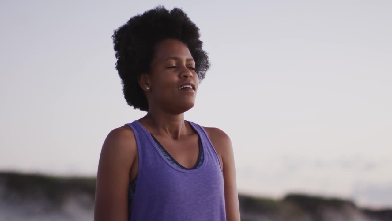 Happy african american woman wearing sports suit on sunny beach