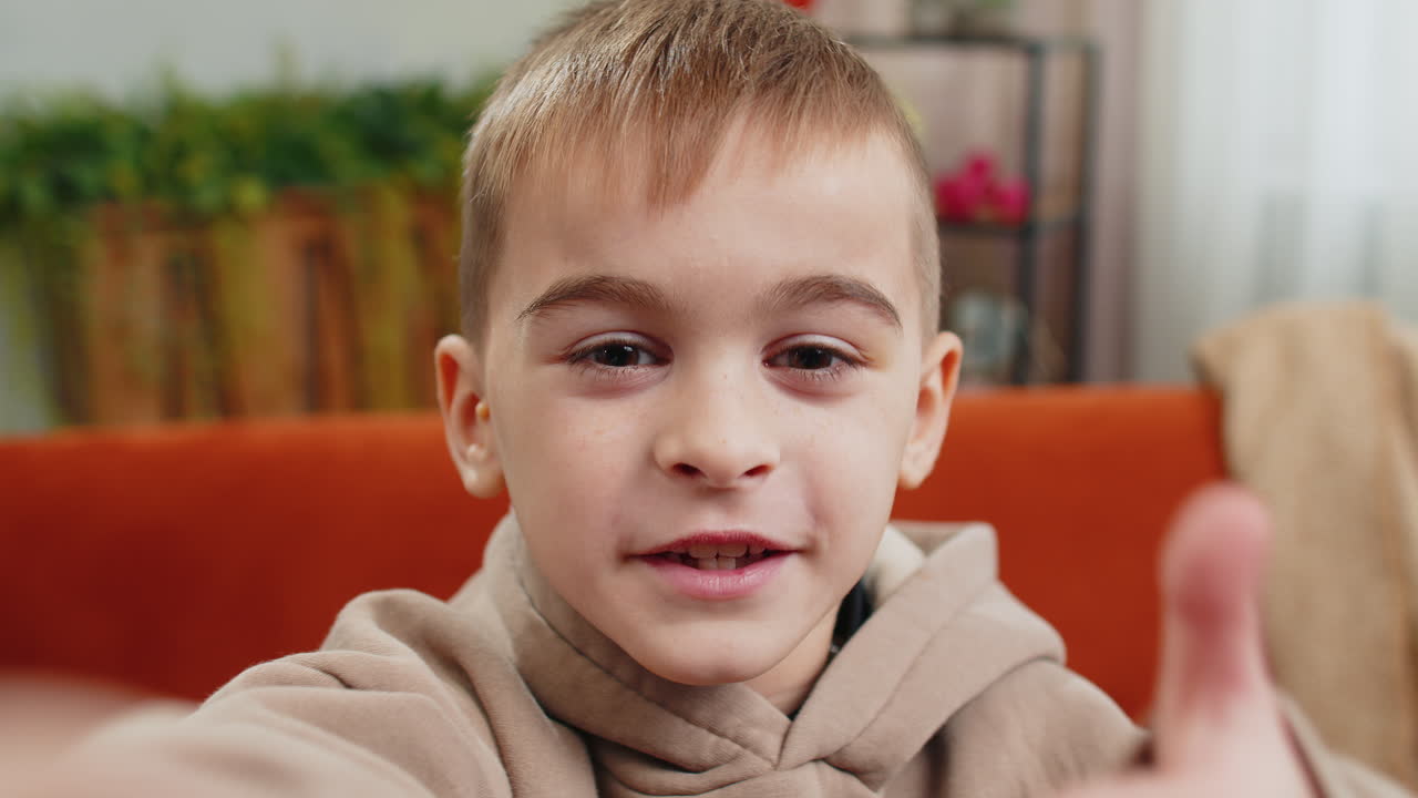Child kid boy taking selfie on smartphone communicating video call home online with subscribers
