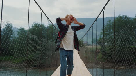 millennial backpacker run nature mountains. cheerful man raise hands on travel.