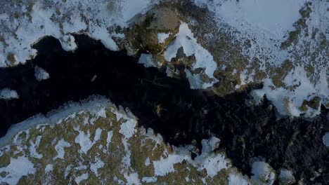 seljalandsfoss river leading to a cascading water over the cliffs in iceland. overhead top down view with tilt up shot by drone