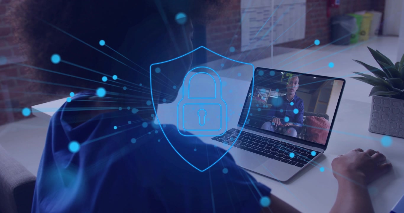 Utente che guarda lo schermo del laptop, mano destra vicino al trackpad, con una clip che inizia ad attivare una sovrapposizione di blocco di sicurezza IT blu