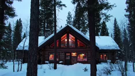 snowy log cabin in the woods at dusk