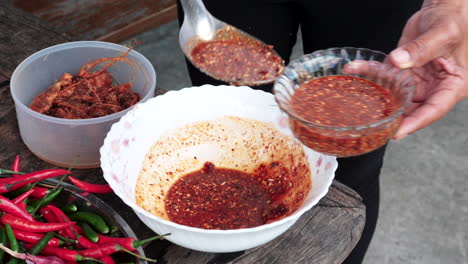 food preparation, person fills glass bowl with fresh spicy sauce - thai cuisine