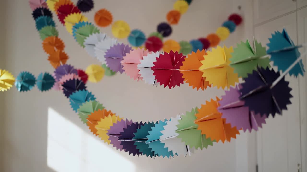 Telecamera che si avvicina a ghirlande di rosoni di carta appese in camera da letto, rivelando pieghe multicolori