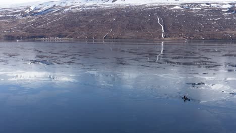 kayaker arriving at beach in iceland fjord, meeting up with group friends, aerial