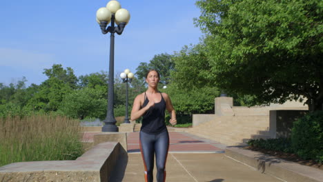 fit millennial girl runs towards camera in the park