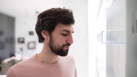 Man-opens-door-of-an-empty-fridge-surprised,-view-from-inside