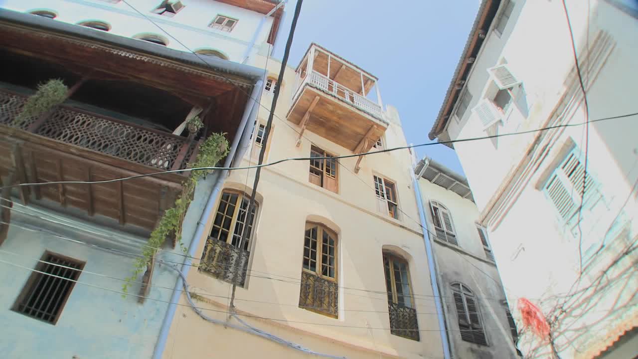 돌 마을 잔지바르의 좁은 골목을 따라 늘어선 크고 오래된 건물을 직접 올려다보는 낮은 각도의 사진