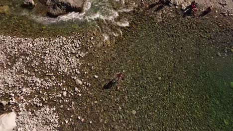 Man-walking-on-the-stones-of-a-flowing-river-or-stream-in-Cajón-Del-Azul,-El-Bolson