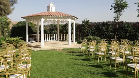 outdoor wedding hall surrounded by trees and full of chairs in a backyard garden establishing or wide shot