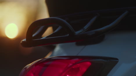 close-up of a scooter's tail light and rear rack at sunset