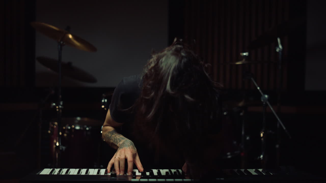 hombre sonriente presionando las teclas en el estudio de música. hombre emocionado tocando el teclado en el interior.