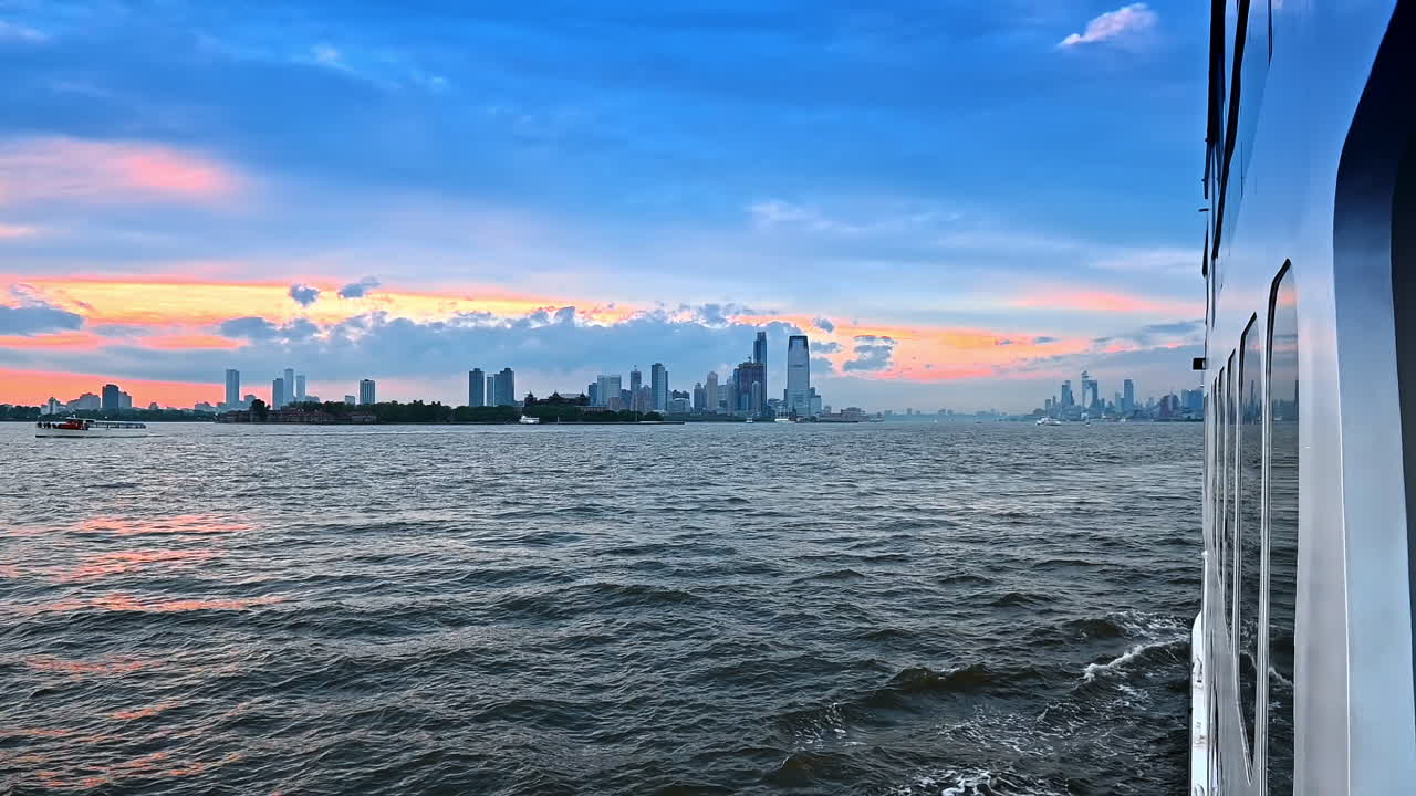Footage from the board of the riverboat moving by the river in New York. Skyline of metropolis at the backdrop of the sky at sunset time