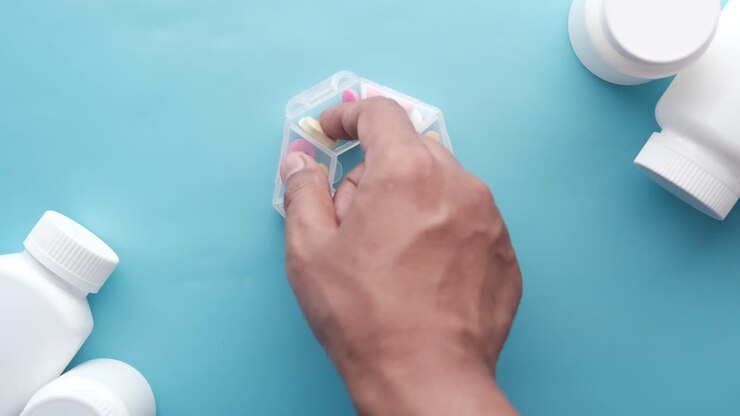 Hand taking pill from a weekly pill organizer