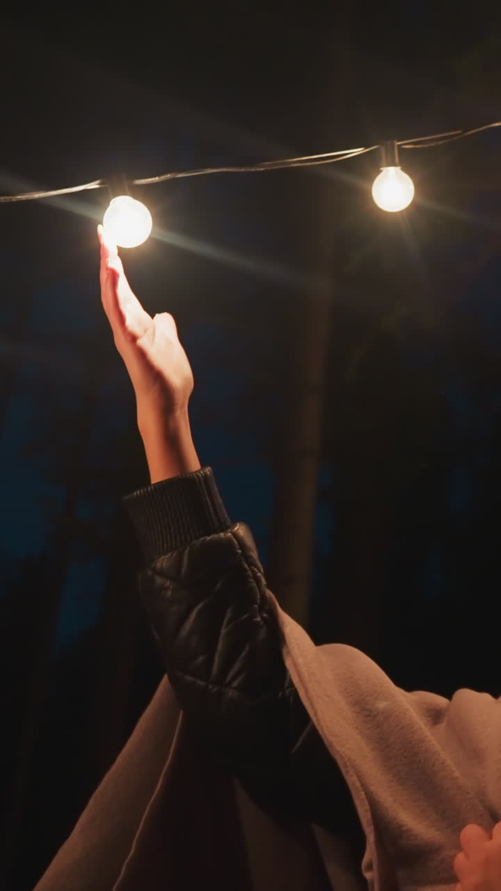 la mujer en la manta toca las luces en el glamping por el bosque. la mujer encuentra la tranquilidad en el silencio y el aislamiento del campamento experimentando una mezcla de relajación y soledad