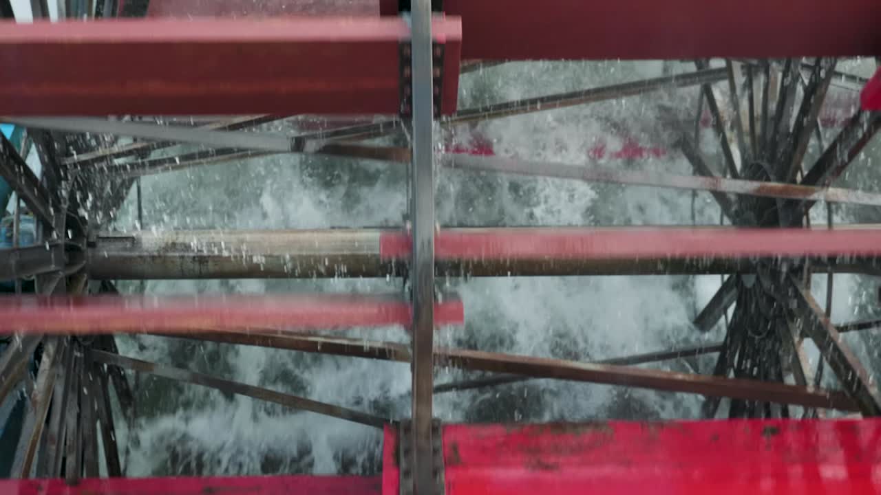 Wheels of Sternwheeler old fashioned ship turning with red paddles in the river splashing the water close up