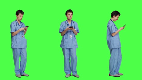 Junge-Krankenschwester-Schreibt-SMS-Auf-Smartphone-Vor-Greenscreen-Hintergrund