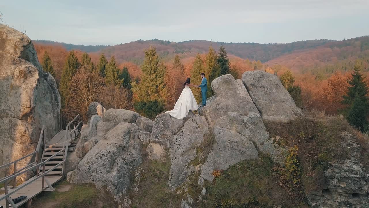 los recién casados están en una ladera alta de la montaña. el novio y la novia.