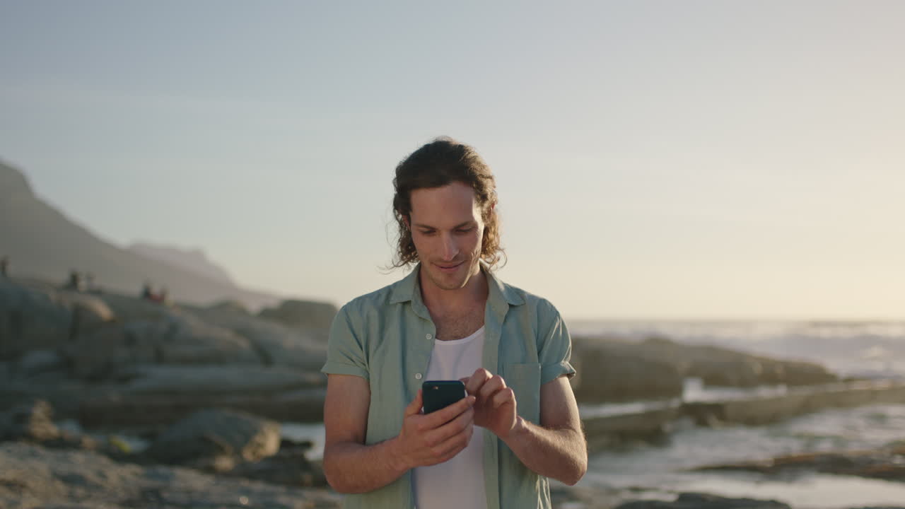 ritratto di un uomo che usa il telefono per inviare messaggi sulla spiaggia al tramonto