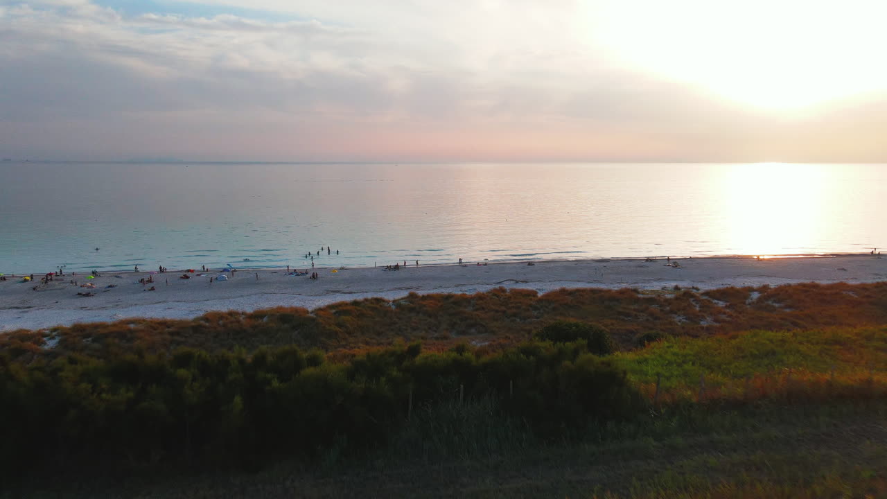 вид сверху на группу людей на пляже, отдыхающих и наслаждающихся вечером, с морскими волнами, касающимися берега в деревне портовенере в италии