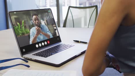 Mujer-Afroamericana-Usando-Una-Computadora-Portátil-Para-Videollamadas,-Con-Un-Colega-De-Negocios-En-La-Pantalla