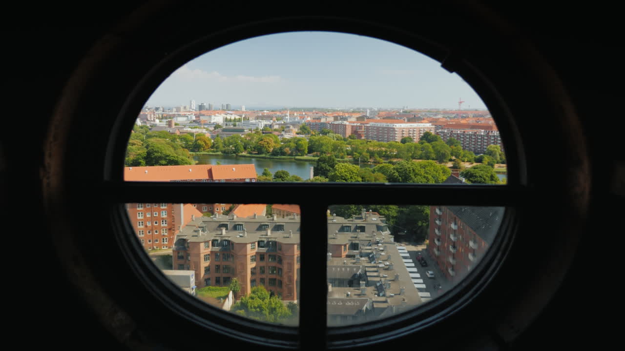 vista de la ciudad de copenhague a través de la antigua ventana redonda de la torre de tornillo video 4k