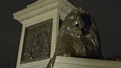 famous bronze lion in trafalgar square at night, london in uk