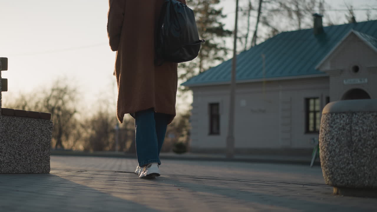 한 소녀가 흐릿한 공원에서 걸어가고 있으며, 은 그녀의 다리와 발에서 시작됩니다. 배경은 부드럽게 초점을 맞추지 않습니다.