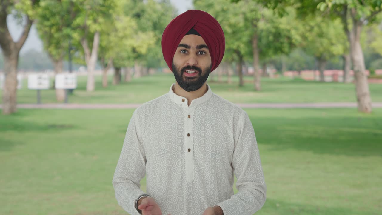 hombre indio sikh serio hablando con la cámara en el parque