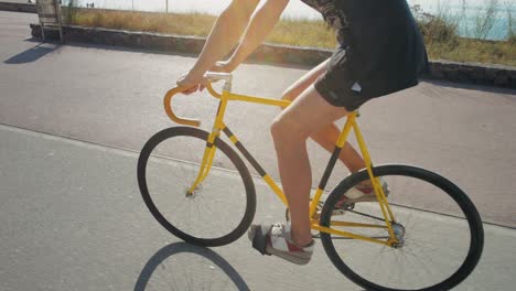 person cycling a yellow fixed gear bike on a coastal path