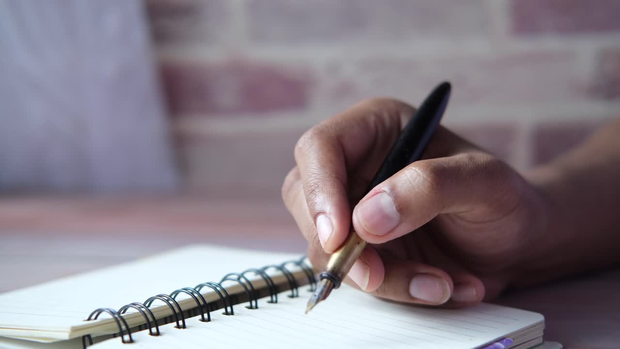 Person Writing in a Notebook with a Fountain Pen