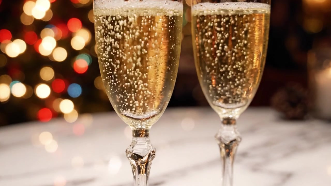 Elegante celebrazione con champagne frizzante in flûte su uno sfondo festivo di luci scintillanti, perfetto per Capodanno o occasioni speciali.
