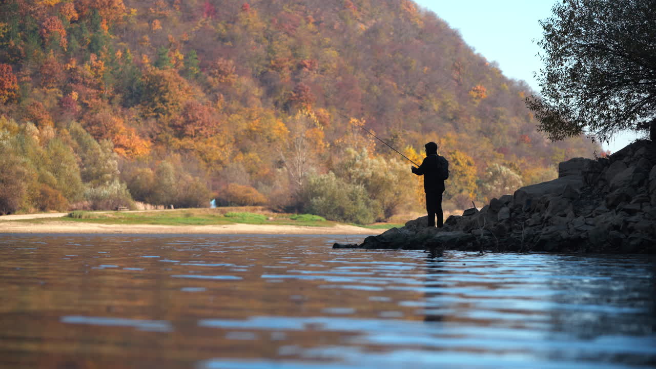Fisherman at a scenic lake in autumn