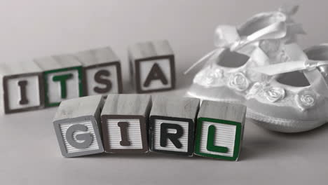 its a girl message in letter blocks beside booties