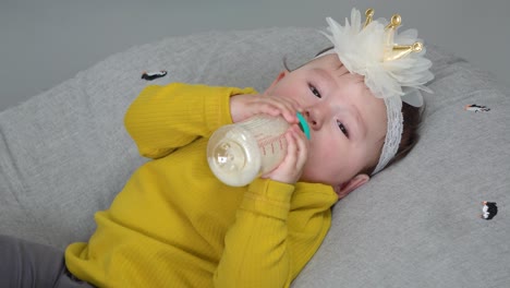 Cute-little-baby-girl-drink-bottle-milk-holding-it-with-two-hands