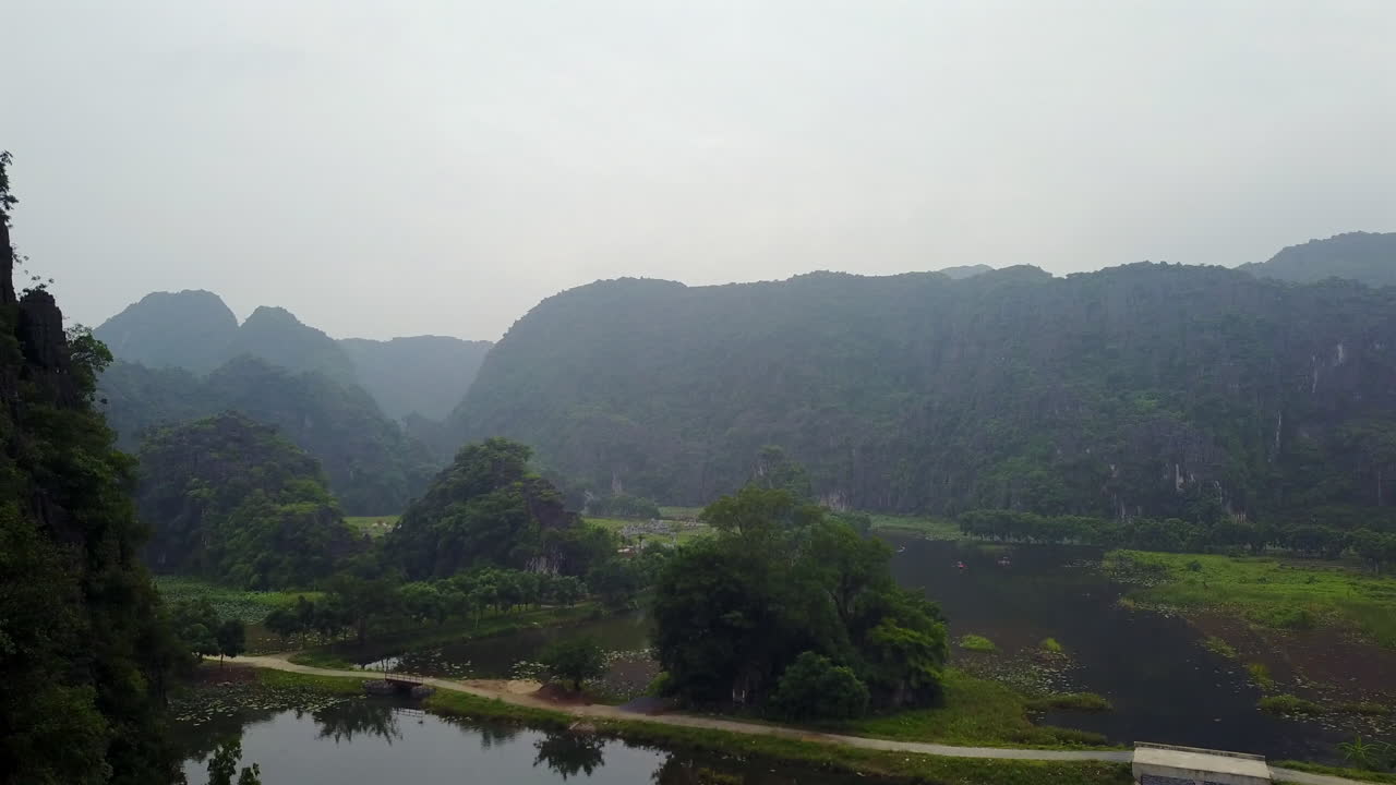 Experience the ethereal beauty of Ninh Binh, Vietnam, as fog gently blankets the iconic rock formations, creating a mystical and serene landscape.